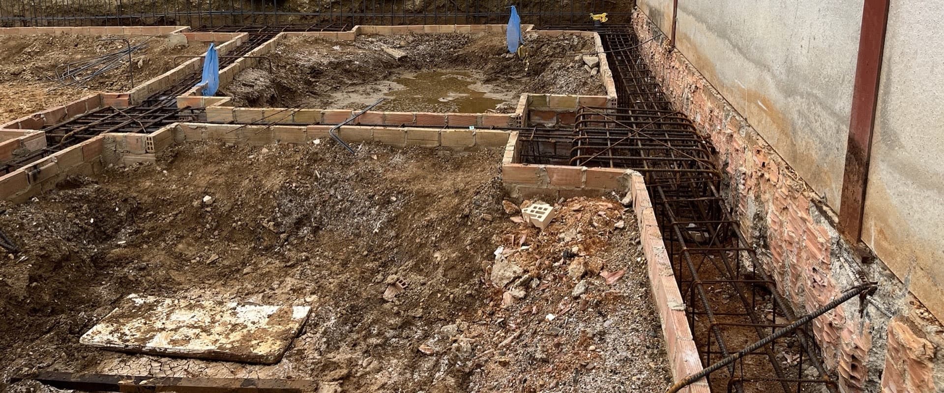 Cimentación de una nave industrial en Lepe junto al muro medianero de una nave existente, con agua acumulada por la lluvia